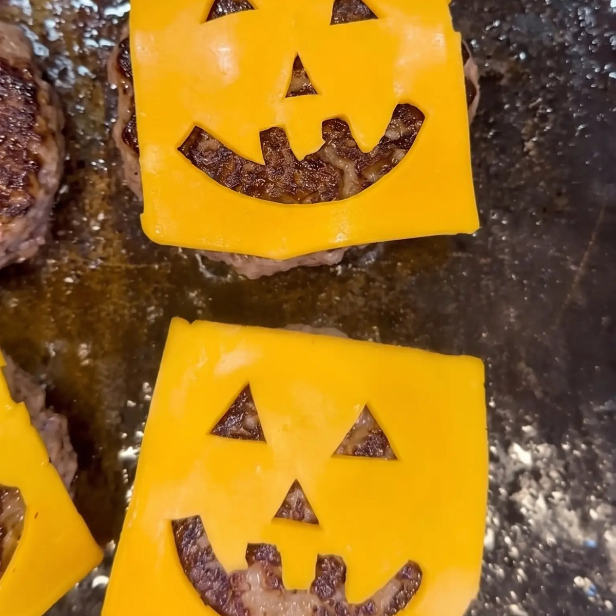Stuffed Jack-O'-Lantern Burgers on the grill, cheese slices with jack-o-lantern faces cut out